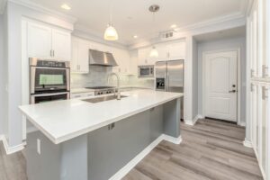 Spacious white kitchen with quartz island and stainless steel appliances